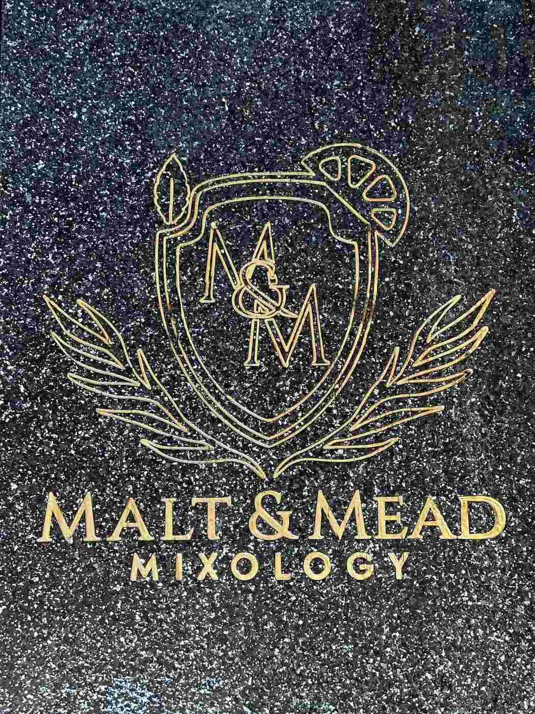 Malt and Mead Mixology logo engraved with gold inlay in black terrazzo concrete